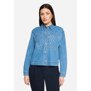 Model i en lys cowboyjakke med diskret glimmer p� lommerne og guldknapper.