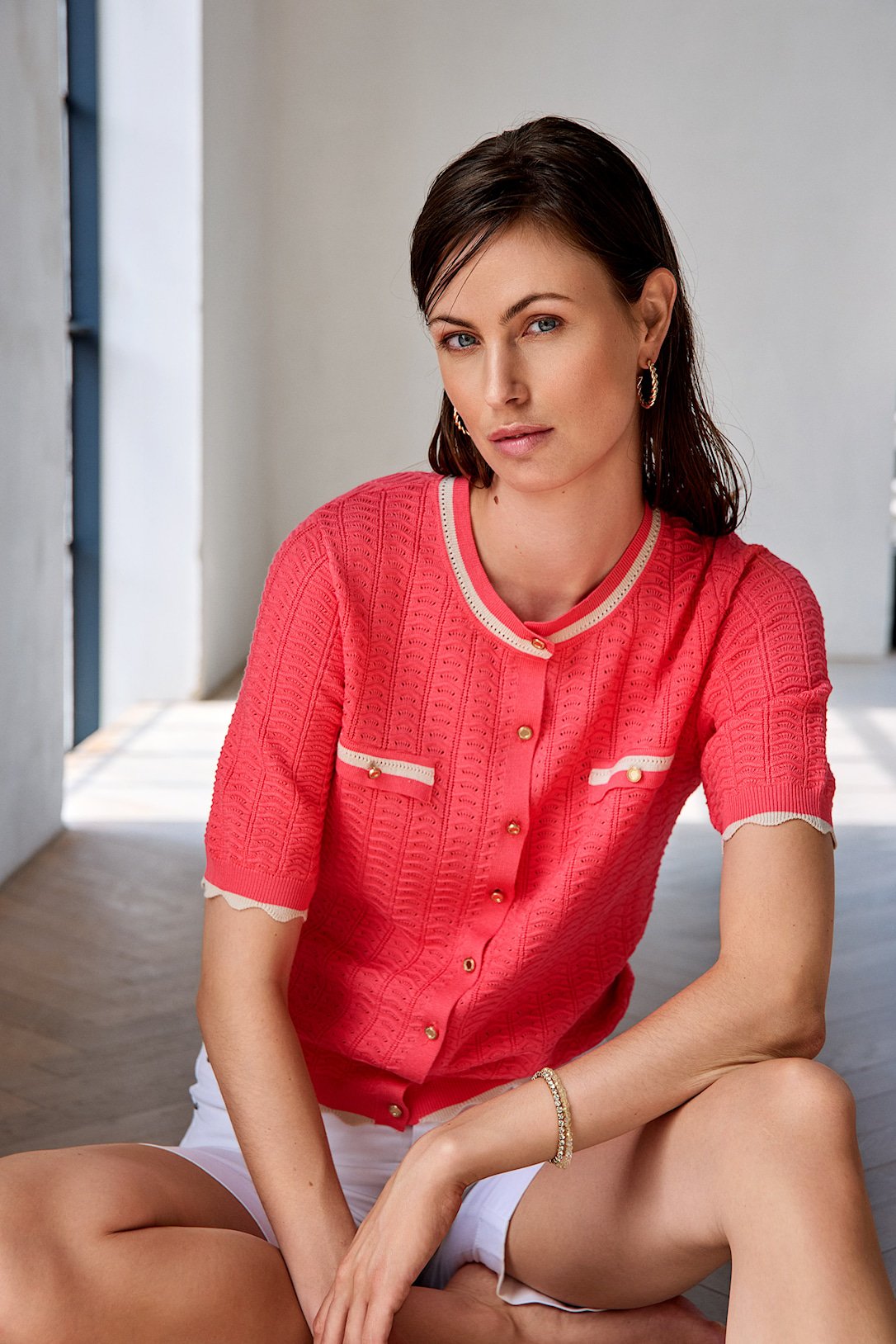 Koralfarvet Micha strikcardigan med beige b�lgede kanter vist p� model